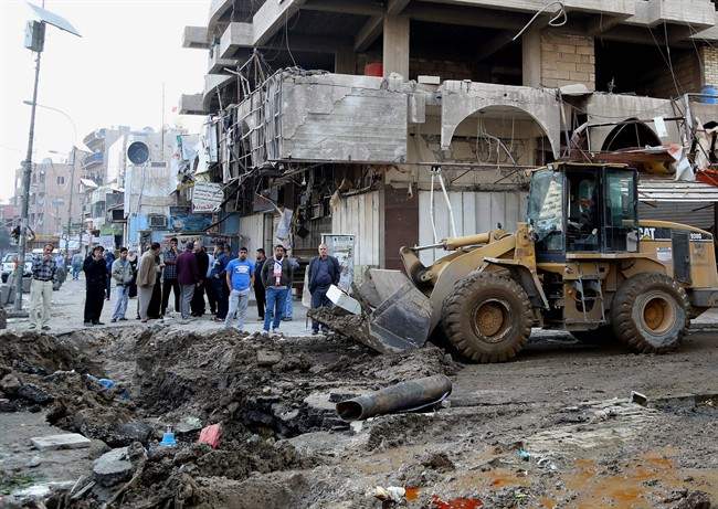 Civilians clear the aftermath of a car bomb attack in the crowded commercial area of Karrada, Baghdad, Iraq, Wednesday, Feb. 26, 2014. A car bombing in Baghdad on Tuesday killed and wound scores of people, said Iraqi officials. Commercial areas are favorite targets to militants seeking to undermine confidence in government efforts to maintain security nationwide. (AP Photo/Hadi Mizban).