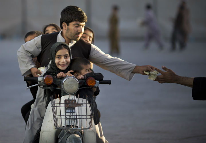 An Afghan man with his five children on his motorbike pays money to enter a park in Kandahar, southern Afghanistan, on Nov. 13, 2013.