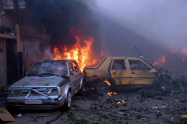 In this photo released by the Syrian official news agency SANA, Flames rise from damaged cars at the site where two car bombs exploded at a commercial street inhabited mostly by members of President Bashar Assad's minority Alawite sect, in Homs province, central Syria, Wednesday April 9, 2014.