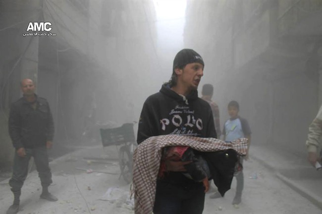 This photo provided by the anti-government activist group Aleppo Media Center (AMC), which has been authenticated based on its contents and other AP reporting, shows a Syrian man carrying the body of a child killed by a government forces airstrike in the Al-Ansari neighborhood, in Aleppo, Syria, Tuesday, April 15, 2014.