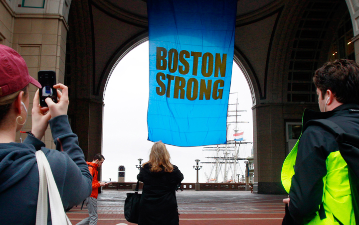 People photograph a banner reading "Boston Strong" as it hangs at Rowes Wharf on the first anniversary of the Boston Marathon bombings, Tuesday, April 15, 2014, in Boston.