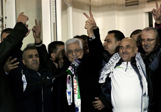 FILE - In this Tuesday, Dec. 31, 2013 file photo, Palestinian President Mahmoud Abbas, center, receives released Palestinian prisoners during a welcome ceremony after their arrival at the Palestinian headquarters in the West Bank city of Ramallah.