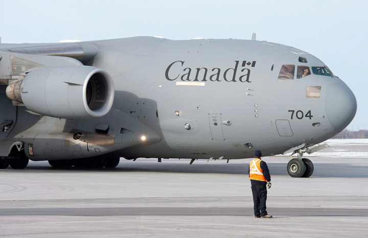 A ground crew member directs a Canadian C17 Globemaster as it arrives carrying the last troops returning from Afghanistan, Tuesday, March 18, 2014 in Ottawa. 