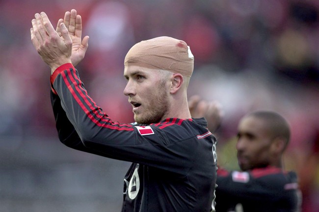 Toronto FC 's Michael Bradley (left) and applauds supporters in Toronto on March 22, 2014. THE CANADIAN PRESS/Chris Young.