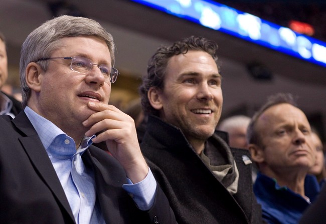 Former Vancouver Canucks captain Trevor Linden, centre, Prime Minister Stephen Harper, left, and MP Stockwell Day watch first period NHL hockey action between the Vancouver Canucks and Minnesota Wild in Vancouver on March 14, 2011. 