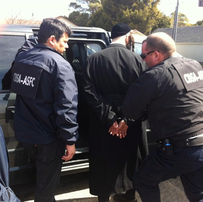 Canada Border Services Agency agents take a member of the ultra-orthodox Jewish sect Lev Tahor into custody in Chatham, Ont., on Wednesday, April 2, 2014. THE CANADIAN PRESS/ho-Ashton Patis, BlackburnNews.com EDS NOTE: Mantatory credit to: Ashton Patis, BlackburnNews.com with the use of this photo.(The Canadian Press).
