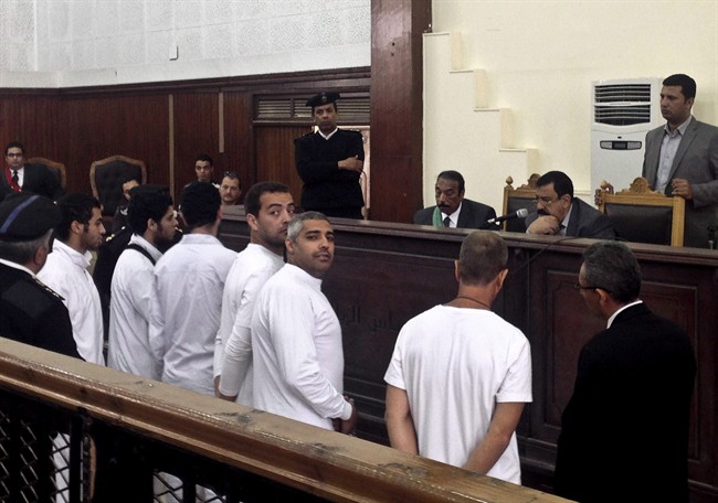 Al-Jazeera English bureau chief Mohamed Fahmy, center, producer Baher Mohamed, center left, and correspondent Peter Greste, second right, stand in a courtroom along with several other defendants during their trial on terror charges, in Cairo, Egypt, March 31, 2014.