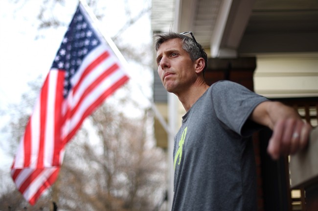Marathon runner Jean-Paul Bedard stands in front of his home in Toronto on Sunday, April 13, 2014 where he is flying an American flag as a tribute to the first-year anniversary of the Boston Marathon bombing. 