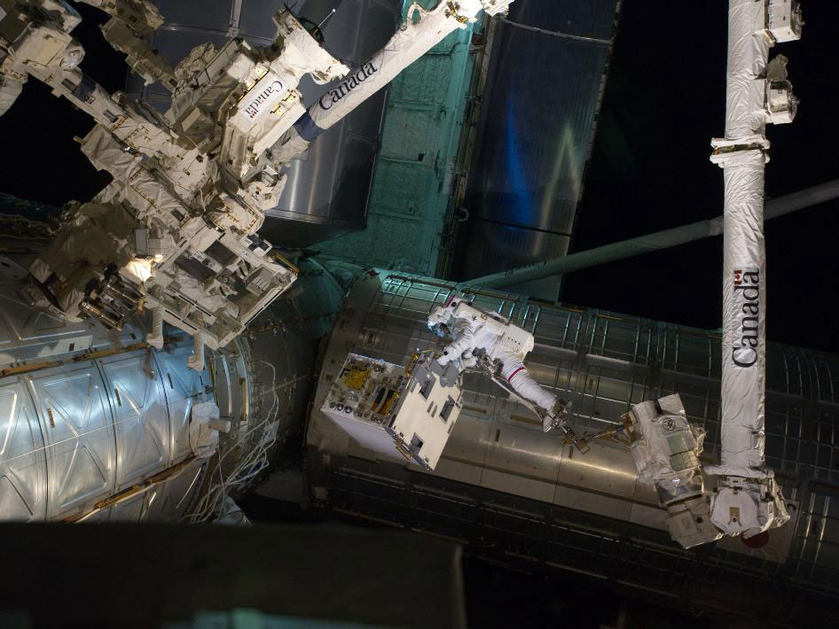 Astronaut Mike Fossum works with Canadarm 2, towards Dextre on the ISS.