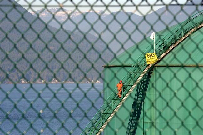 An activist walks up the stairs of an oil storage tank at the Kinder Morgan facility in Burrard Inlet, B.C. on Oct. 16, 2013. THE CANADIAN PRESS/Jonathan Hayward.