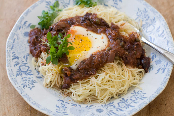 This photo shows eggs in puttanesca with angel hair pasta