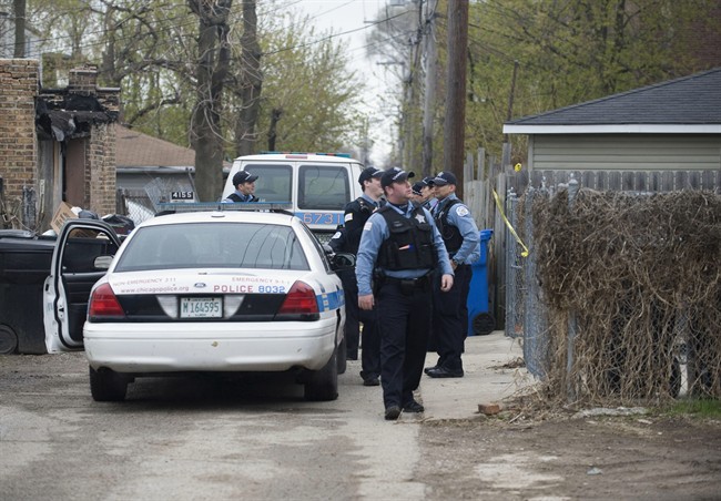 In this Monday, April 28, 2014 photo, police stand outside a residence in Chicago after 14-year-old girl was fatally shot and another girl wounded in the Back of the Yards neighbourhood in Chicago.