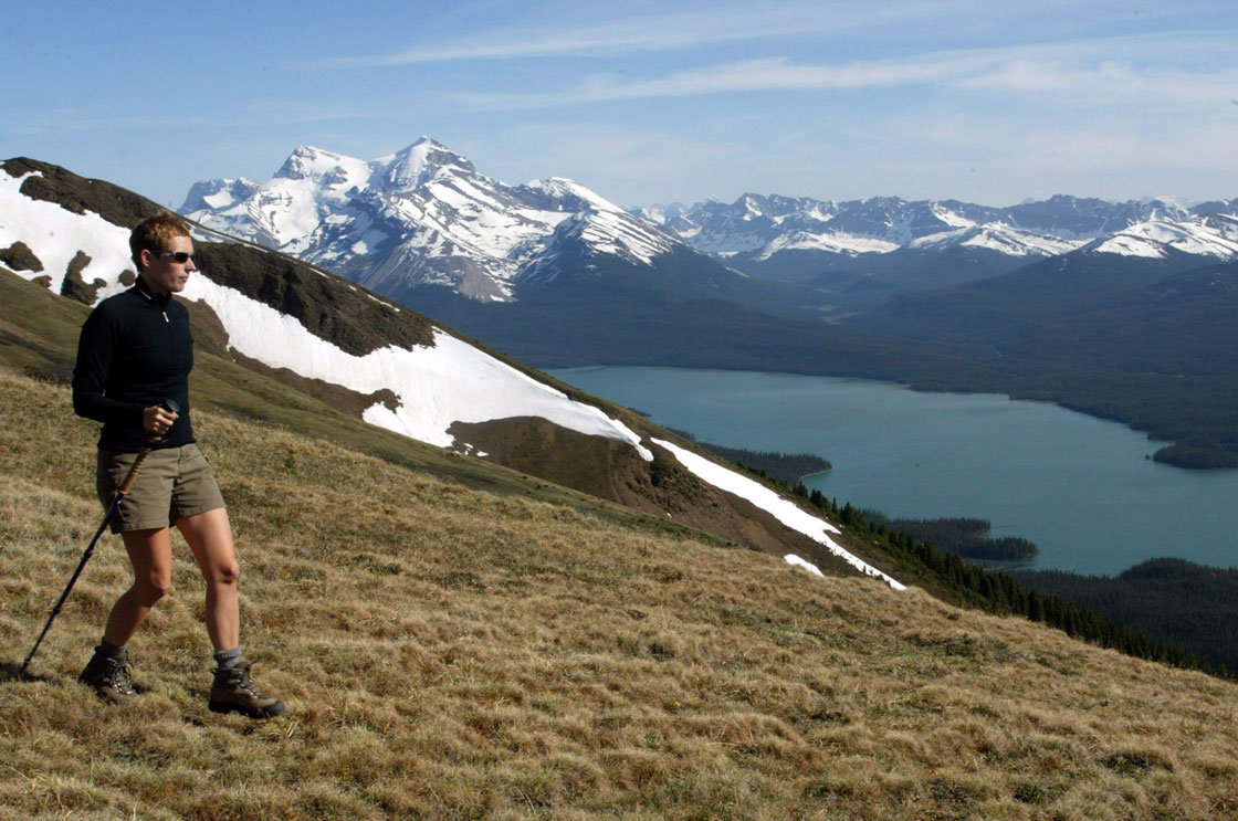 Nice view if you can afford to get there: A hiker takes in the snow covered mountains surrounding Maligne Lake in Jasper National Park. The park is a four hour drive from Calgary.