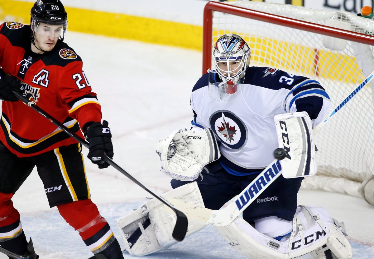 Winnipeg Jets goalie Michael Hutchinson, right, makes a save on a tip by Calgary Flames' Curtis Glencross during third period NHL action in Calgary, Alta., Friday, April 11, 2014. 
