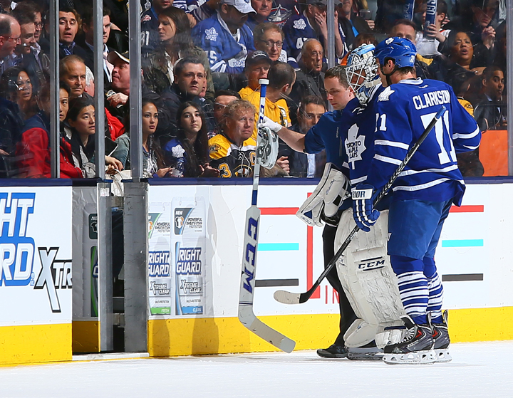 Jonathan Bernier #45 of the Toronto Maple Leafs is helped off the ice by David Clarkson