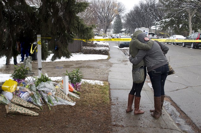 Women cry and hug beside a makeshift memorial near the scene of the multiple fatal stabbings in northwest Calgary on Wednesday, April 16, 2014. 