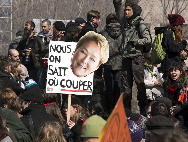 A protester holds a sihn reading "We know where to Cut" with a photo of Quebec Premier Pauline Marois during a against anti-austerity measures Thursday, April 3, 2014 in Montreal.