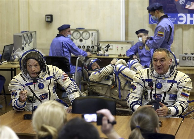 In this Tuesday, March 25, 2014 file photo, U.S. astronaut Steven Swanson, left, and Russian cosmonaut Alexander Skvortsov, crew members of the mission to the International Space Station, speak with relatives during pre-launch preparations at the Russian-leased Baikonur cosmodrome in Kazakhstan. 