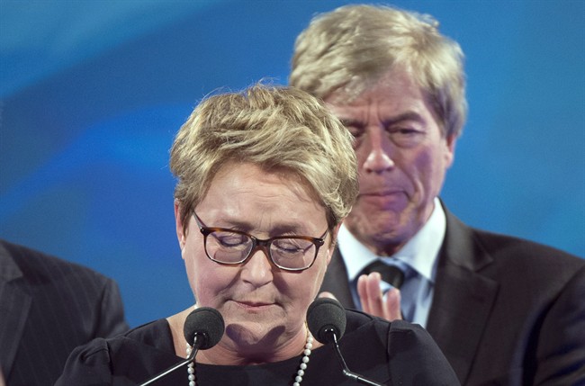 PQ leader Pauline Marois pauses during her speech as her husband Claude Blanchet (rear) applauds at the party's election headquarters Monday, April 7, 2014 in Montreal.