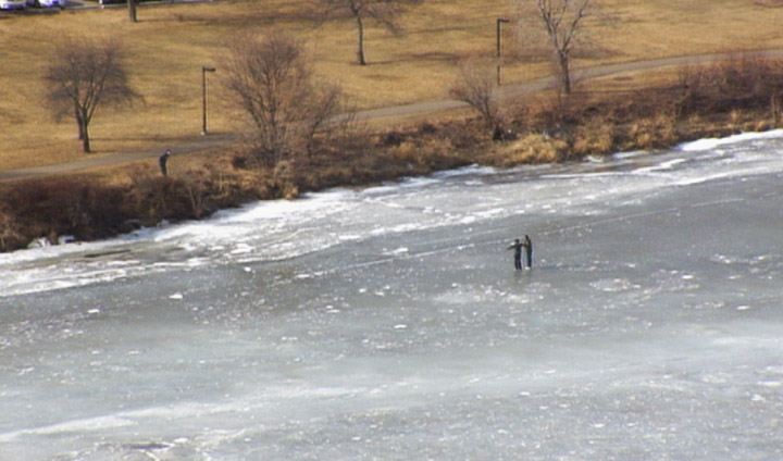 Photo of two people walking on South Saskatchewan River ice on Sunday in Saskatoon.