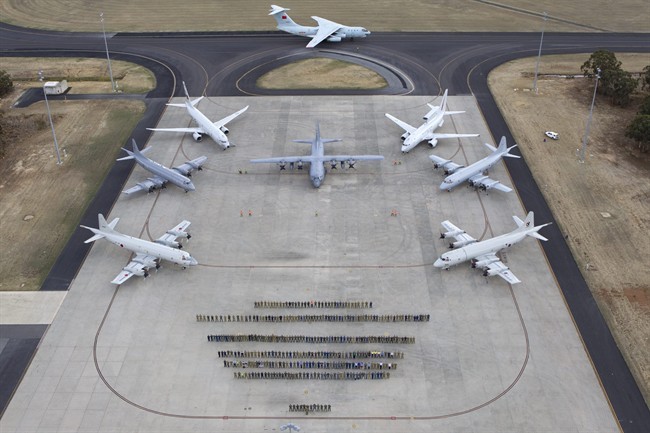In this aerial photo taken April 29, 2014 provided by the Australia Defence Force, multinational air-crew and aircraft involved in operation "Southern Indian Ocean" are assembled for a photo at RAAF Base Pearce, in Perth, Western Australia. Seven nations, including Australia, New Zealand, the U.S., South Korea, Malaysia, China and Japan, have flew daily search mission out to the southern Indian Ocean in the massive multinational hunt for the missing Malaysia Airlines Flight 370.