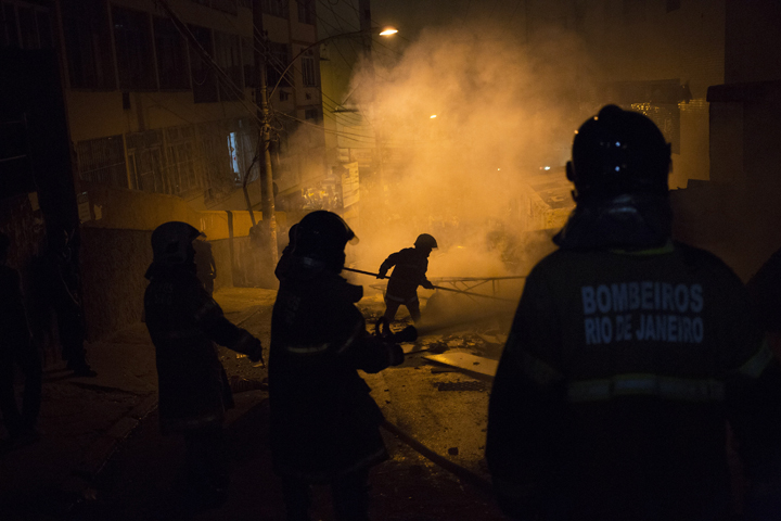Firefighters put out a burning barricade during clashes at the Pavao Pavaozinho slum in Rio de Janeiro, Brazil, Tuesday, April 22, 2014.