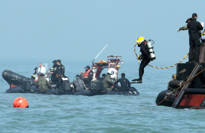 A diver jumps into the sea to look for people believed to have been trapped in the sunken Sewol ferry near buoys which were installed to mark the vessel in the water off the southern coast near Jindo Korea, Thursday, April 24, 2014.