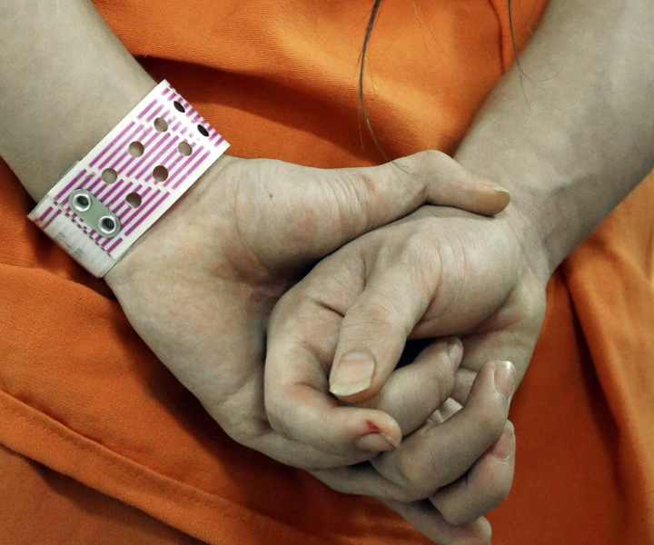 In this Dec. 10, 2013 an inmate wears his special purple wrist band in a new unit in the Harris County Jail for gay, bisexual and transgender inmates in Houston.  