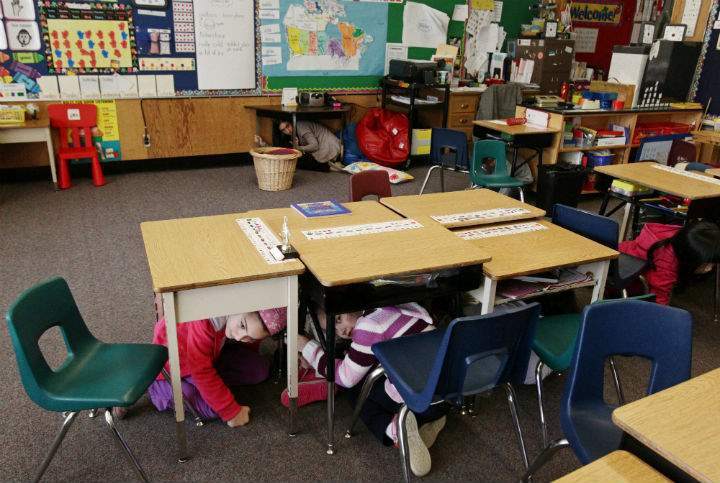 Grade one student Nikki Hessami, lower left, and grade two student Anita Zamanigohar take cover under their desks during an earthquake drill at Hollyburn Elementary School in West Vancouver, B.C., on Wednesday January 26, 2011.