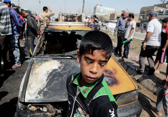 Civilians inspect the site of a car bomb attack in Baghdad's Sadr City neighbourhood, Iraq, Wednesday, April 9, 2014.