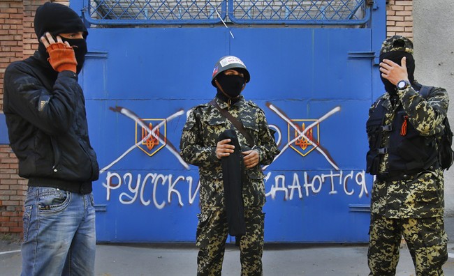 Pro Russian militants stand in front of a gate with graffiti reading "Russ. Russian do not surrender", in Slovyansk , eastern Ukraine.