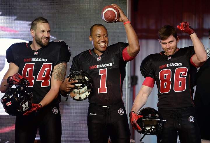Redblacks veteran CFL quarter back Henry Burris sports the team's home uniform alongside teammates teammates Justin Phillips, left, and Simon Le Marquand in Ottawa on Tuesday, May 6, 2014. THE CANADIAN PRESS/Sean Kilpatrick.