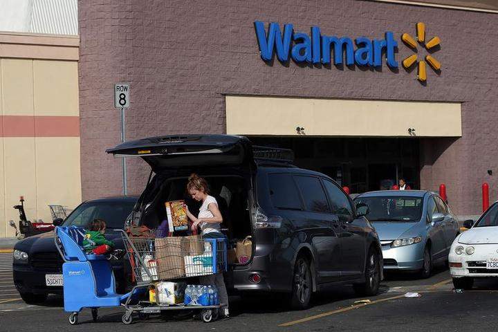 A Wal-Mart customer loads groceries into her car outside of a Wal-Mart store.