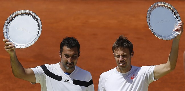 Daniel Nestor from Canada, right and Nenad Zimonjic from Serbia , left, hold their trophies after a Madrid Open tennis tournament doubles final match against Bob Bryan and Mike Bryan from the U.S, in Madrid, Spain, Sunday, May 11, 2014. (AP Photo/Andres Kudacki).