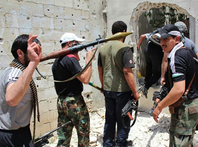 Syrian rebels hold their weapons as they prepare to fight against Syrian troops in Homs province, Syria, in June 2012.