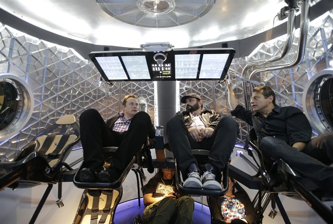Elon Musk, left, CEO and CTO of SpaceX, mingles with invited guests inside the SpaceX Dragon V2 spaceship at the headquarters on Thursday, May 29, 2014, in Hawthorne, Calif.