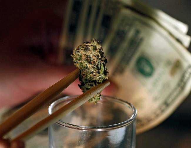 FILE -- In this Sept. 18, 2012 file photo a caregiver picks out a marijuana bud for a patient at a marijuana dispensary in Denver. 