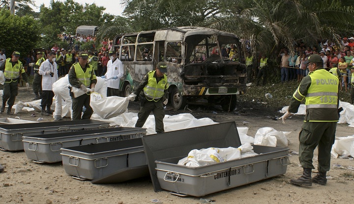 Police carry bags containing the remains of children who burned to death in the bus parked behind in Fundacion in northern Colombia, Sunday, May 18, 2014. 