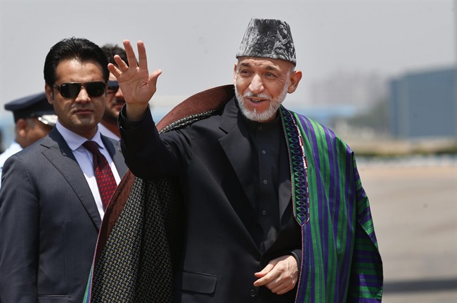 Afghan President Hamid Karzai waves upon arrival for the swearing in ceremony of India's prime minister elect Narendra Modi in New Delhi, India, Monday, May 26, 2014.