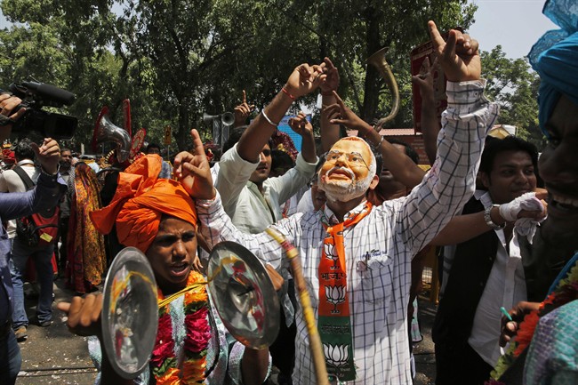 A Bharatiya Janata Party (BJP) supporter wears a mask Narendra Modi, India\’s next prime minister, and celebrates after preliminary results showed the BJP winning by a landslide, outside the party headquarter in New Delhi, India, Friday, May 16, 2014.