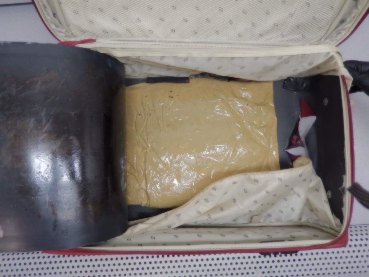 Seized suspected heroin and false bottom suitcase used to conceal the narcotics.
