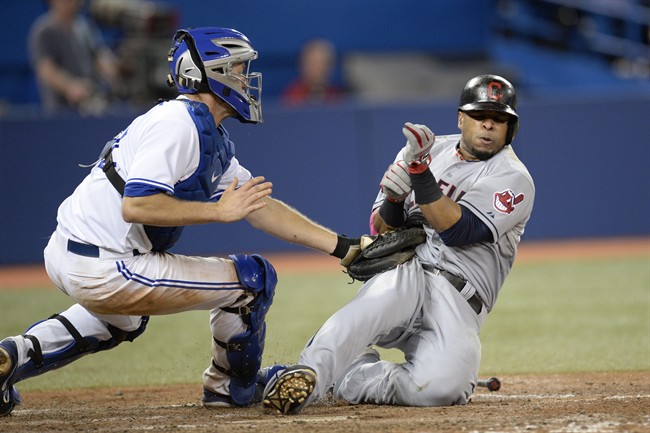 Toronto Blue Jays' Josh Thole tags out Cleveland Indians' Carlos Santana at home plate to end the top of the eighth inning American League baseball action in Toronto on Tuesday, May 13, 2014. THE CANADIAN PRESS/Frank Gunn.