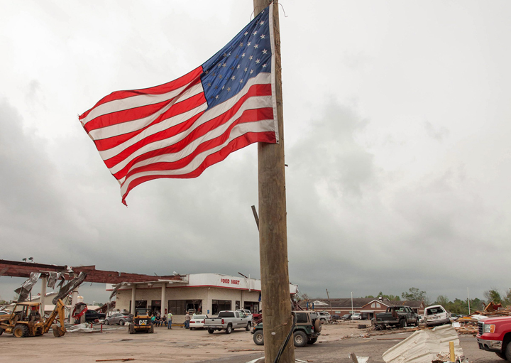 An American flag flies from a broken electrical pole along Highway 64 in Vilonia, Ark., on Monday, April 28, 2014 after a tornado struck the town.