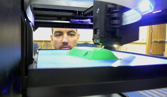 In this May 20, 2014 photo, Michael Fieldson , the civilian project manager for the US Special Operations Command's Tactical Assault Light Operator Suit at MacDill Air Force Base, looks at a 3D printer during a trade show in Tampa, Fla.