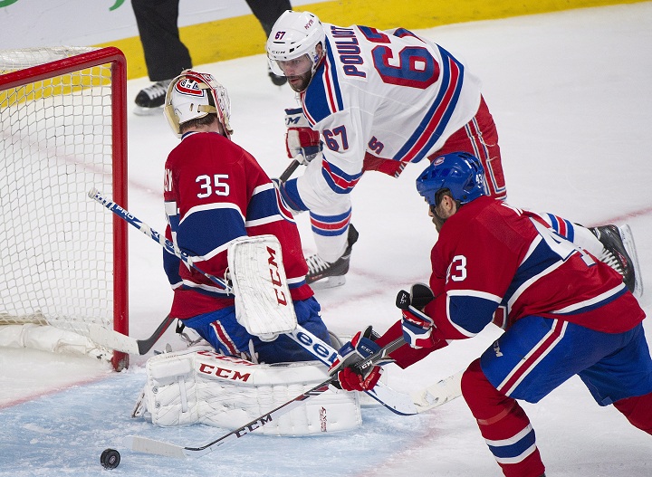 Montreal Canadiens goaltender Dustin Tokarski, left, loses the puck as New York Rangers' Benoit Pouliot, right, moves in as Canadiens' Mike Weaver defends during third period in game two of the NHL Eastern Conference final Stanley Cup playoff action in Montreal, Monday, May 19, 2014. 