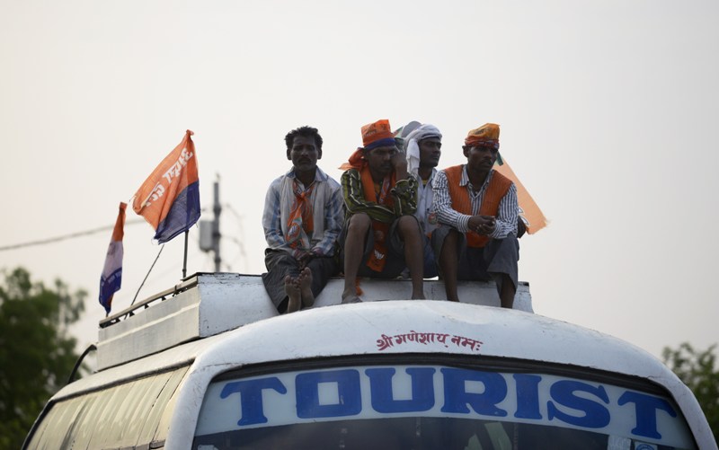 Supporters of India election frontrunner Narendra Modi sit on top of a bus as they wait to go home after attending a political rally by Modi in Mirzapur on May 9, 2014. Modi, a hardline Hindu nationalist, is widely expected to lead his party to victory in the general election and win the contest in Varanasi when results are announced on Friday, May 16. AFP PHOTO/Roberto SCHMIDT .