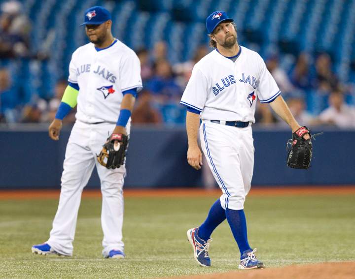 Toronto Blue Jays starting pitcher R.A Dickey walks back to the mound after he and third baseman Juan Francisco, left, failed to field a bunt that stayed fair in the sixth inning of their AL baseball game against the Kansas City Royals in Toronto Thursday May 29, 2014.