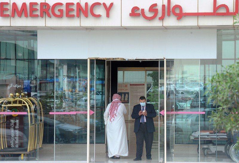 A man, wearing a mouth and nose mask, checks his phone as he leaves the hospital's emergency department on April 27, 2014 in the Saudi capital Riyadh. 