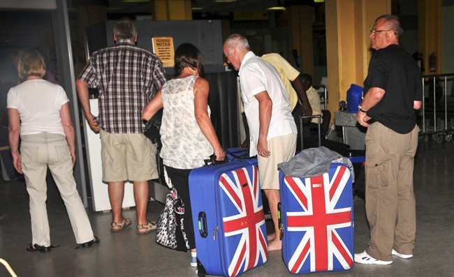 In this photo taken late Thursday, May 15, 2014, British tourists queue to prepare to leave the international airport in Mombasa, Kenya. 