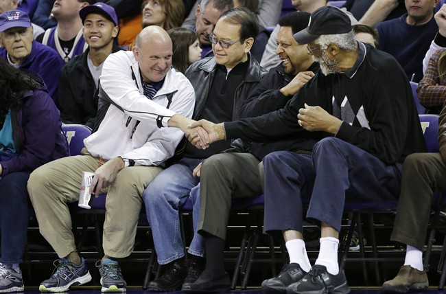 In this Jan. 25, 2014 file photo, then-Microsoft CEO Steve Ballmer, left, shakes hands with former NBA players Bill Russell, right, and "Downtown" Freddie Brown as Omar Lee looks on during an NCAA college basketball game between Washington and Oregon State in Seattle.